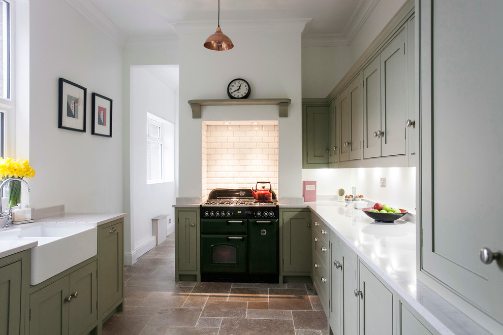 Photo of a mid-sized contemporary galley separate kitchen in Kent with a farmhouse sink, shaker cabinets, quartzite benchtops, white splashback, coloured appliances, limestone floors, green cabinets, subway tile splashback and white benchtop.