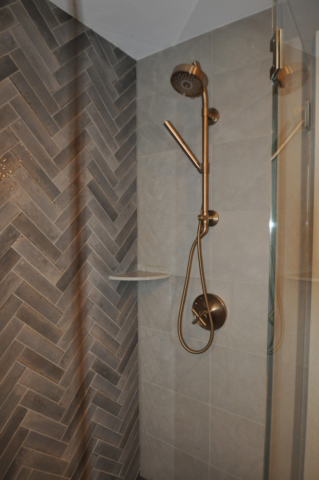Пример оригинального дизайна: ванная комната среднего размера в стиле неоклассика (современная классика) с серыми фасадами, душем без бортиков, инсталляцией, бежевой плиткой, керамогранитной плиткой, бежевыми стенами, полом из керамогранита, душевой кабиной, подвесной раковиной, столешницей из известняка, серым полом, душем с распашными дверями, серой столешницей, тумбой под одну раковину и подвесной тумбой