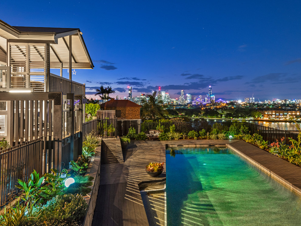 This is an example of a large transitional backyard rectangular pool in Brisbane with decking.