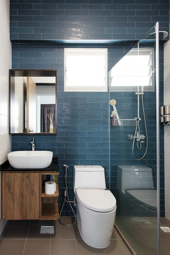 Inspiration for a contemporary 3/4 bathroom in Singapore with flat-panel cabinets, medium wood cabinets, a corner shower, a one-piece toilet, blue tile, subway tile, white walls, a vessel sink, grey floor and an open shower.