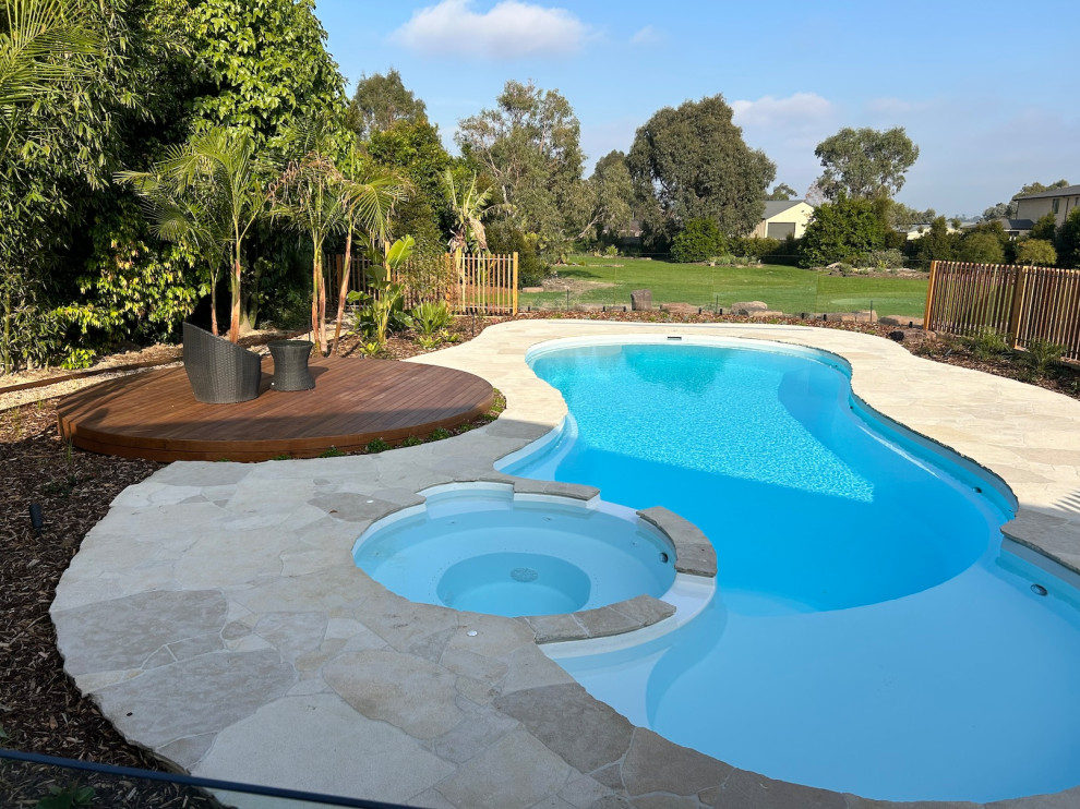 Large contemporary backyard custom-shaped natural pool in Melbourne with with a pool and natural stone pavers.