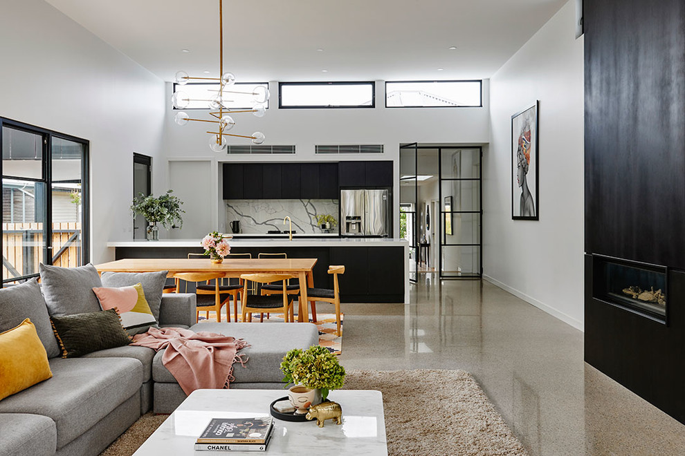 Modern living room in Geelong with white walls, concrete floors, a wood fireplace surround and grey floor.
