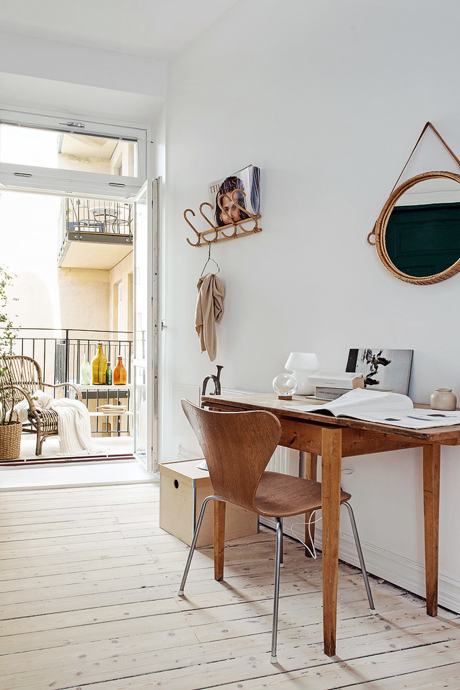 This is an example of a mid-sized scandinavian study room in Gothenburg with white walls, light hardwood floors, no fireplace and a freestanding desk.