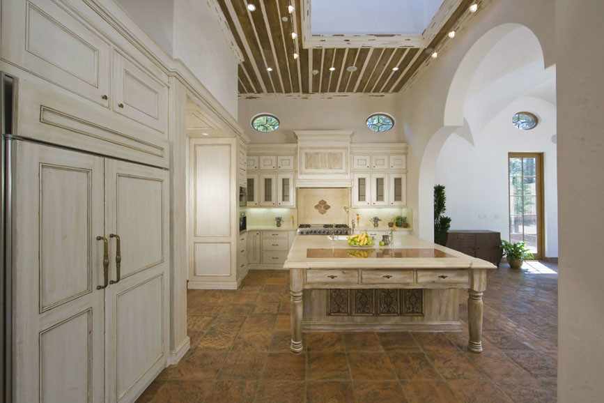 Mid-sized galley terra-cotta tile kitchen pantry photo with beige cabinets, limestone countertops, beige backsplash, custom tile backsplash, paneled appliances, white walls and an island