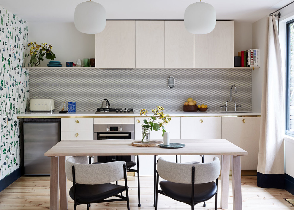 This is an example of a contemporary single-wall eat-in kitchen in Melbourne with an undermount sink, flat-panel cabinets, light wood cabinets, stainless steel appliances, light hardwood floors and no island.
