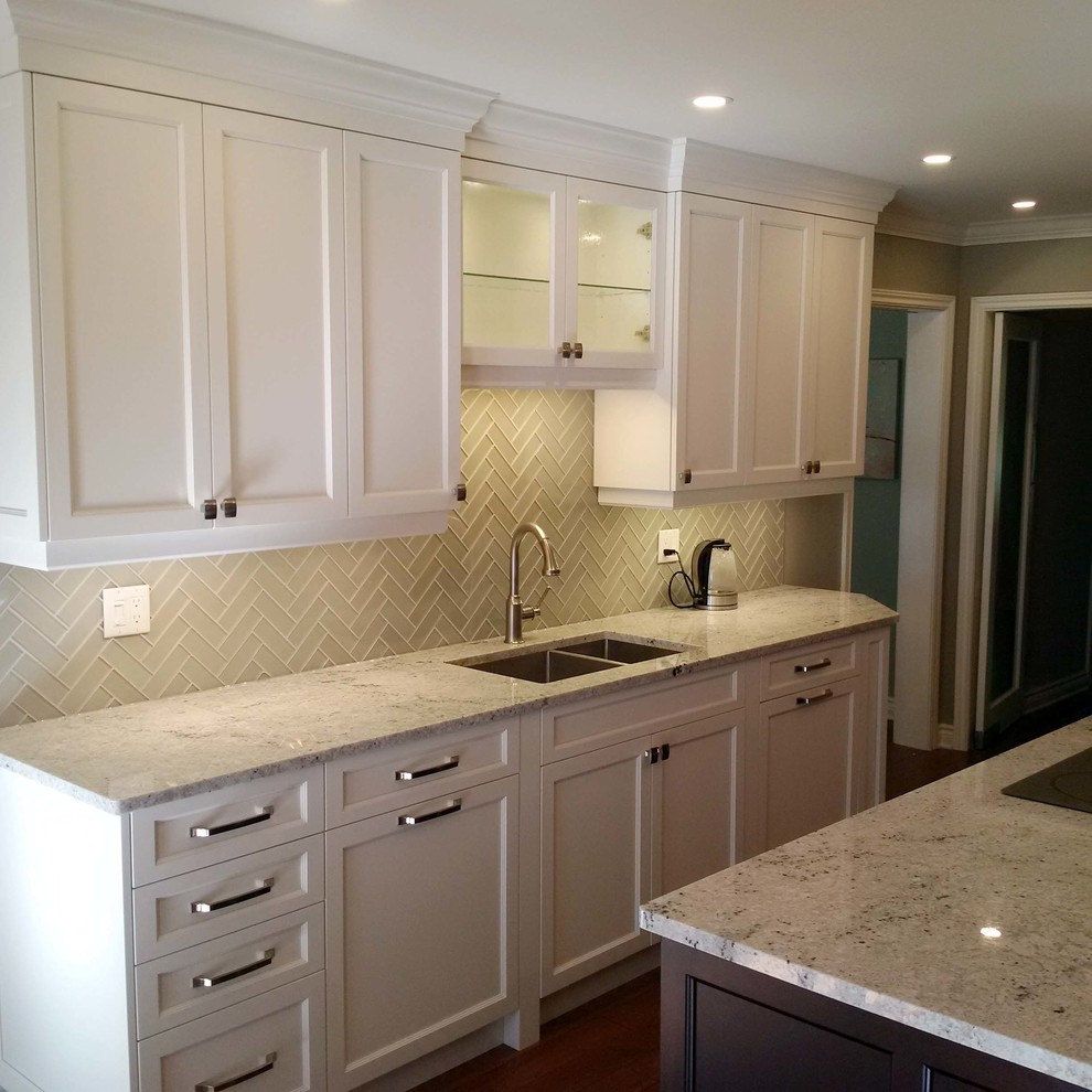 Large transitional l-shaped kitchen in Ottawa with a double-bowl sink, recessed-panel cabinets, white cabinets, granite benchtops, beige splashback, glass tile splashback, stainless steel appliances, dark hardwood floors and with island.
