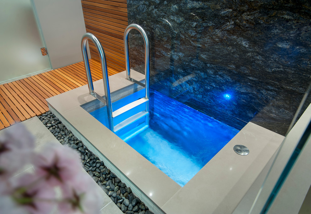 Modern indoor rectangular pool in Vancouver with a hot tub and tile.