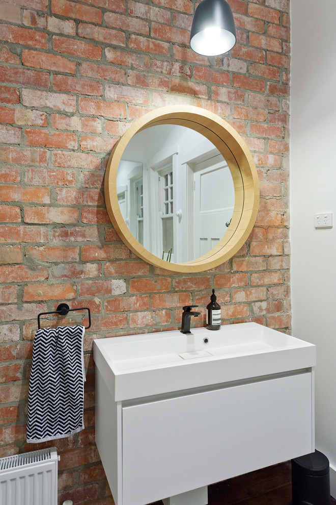 Inspiration for a mid-sized contemporary 3/4 bathroom in Melbourne with flat-panel cabinets, light wood cabinets, a freestanding tub, a wall-mount toilet, white tile, porcelain tile, painted wood floors, a pedestal sink and engineered quartz benchtops.