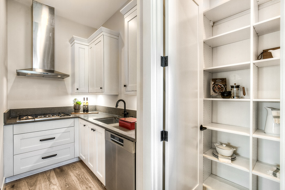 Inspiration for an expansive transitional l-shaped open plan kitchen in Seattle with an undermount sink, recessed-panel cabinets, white cabinets, stainless steel appliances, light hardwood floors, with island and grey benchtop.