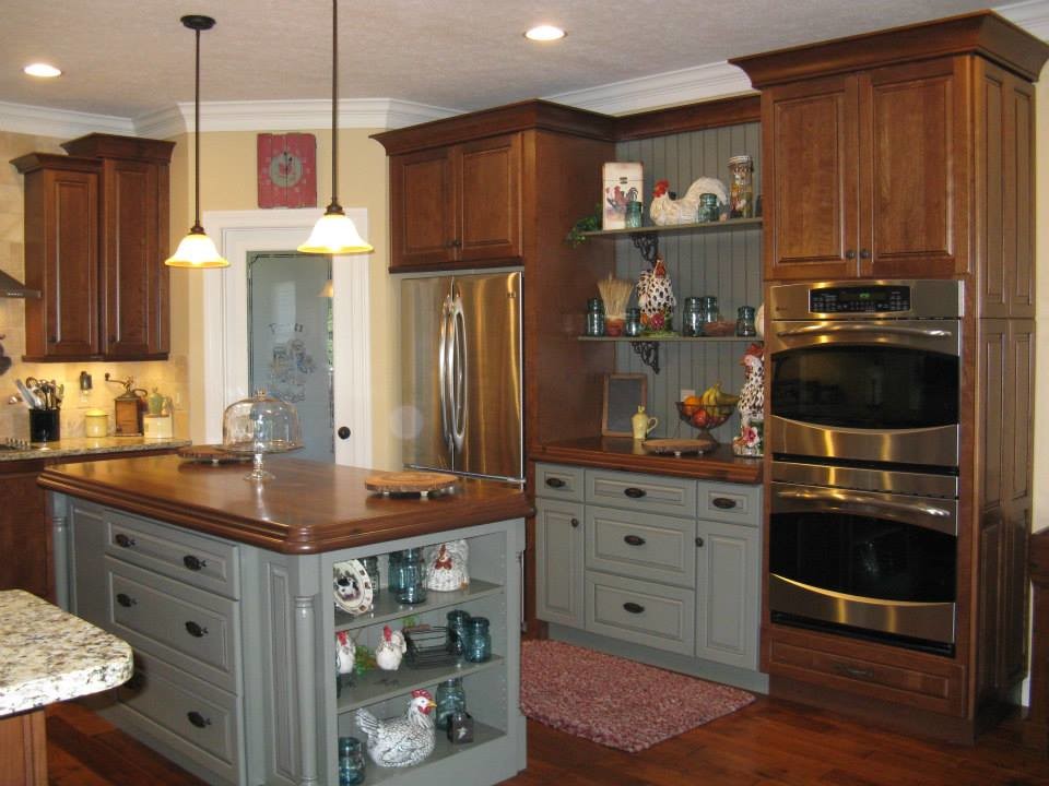 Kitchen - mid-sized rustic u-shaped medium tone wood floor kitchen idea with a double-bowl sink, raised-panel cabinets, medium tone wood cabinets, wood countertops, beige backsplash, stone tile backsplash, stainless steel appliances and an island