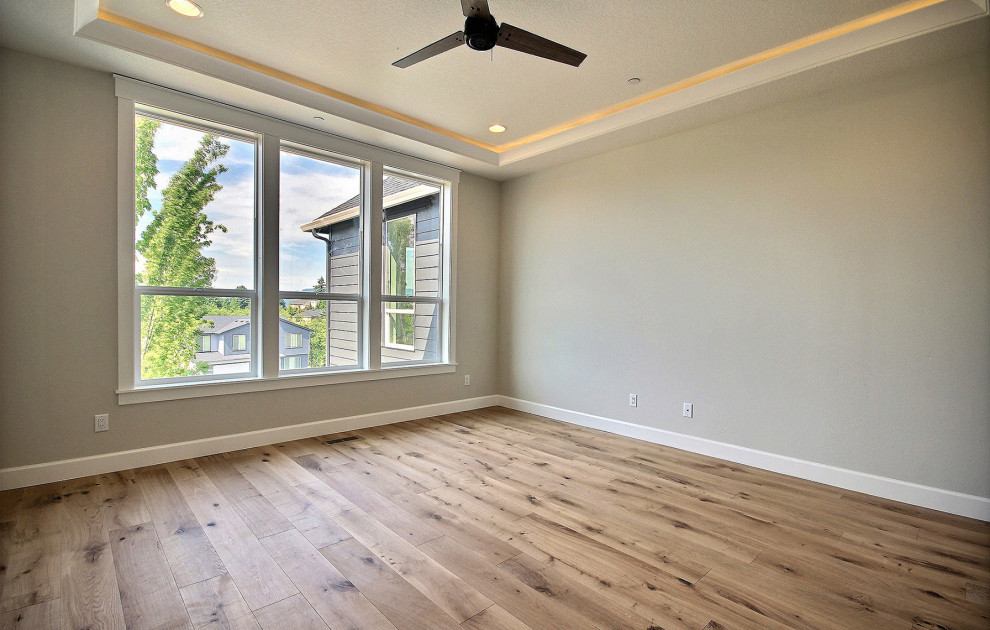 Photo of a large transitional master bedroom in Portland with beige walls, light hardwood floors and beige floor.