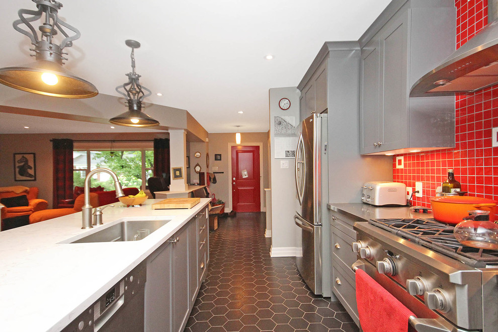 This is an example of a mid-sized eclectic galley eat-in kitchen in Ottawa with an undermount sink, recessed-panel cabinets, grey cabinets, quartz benchtops, red splashback, ceramic splashback, stainless steel appliances, ceramic floors and with island.