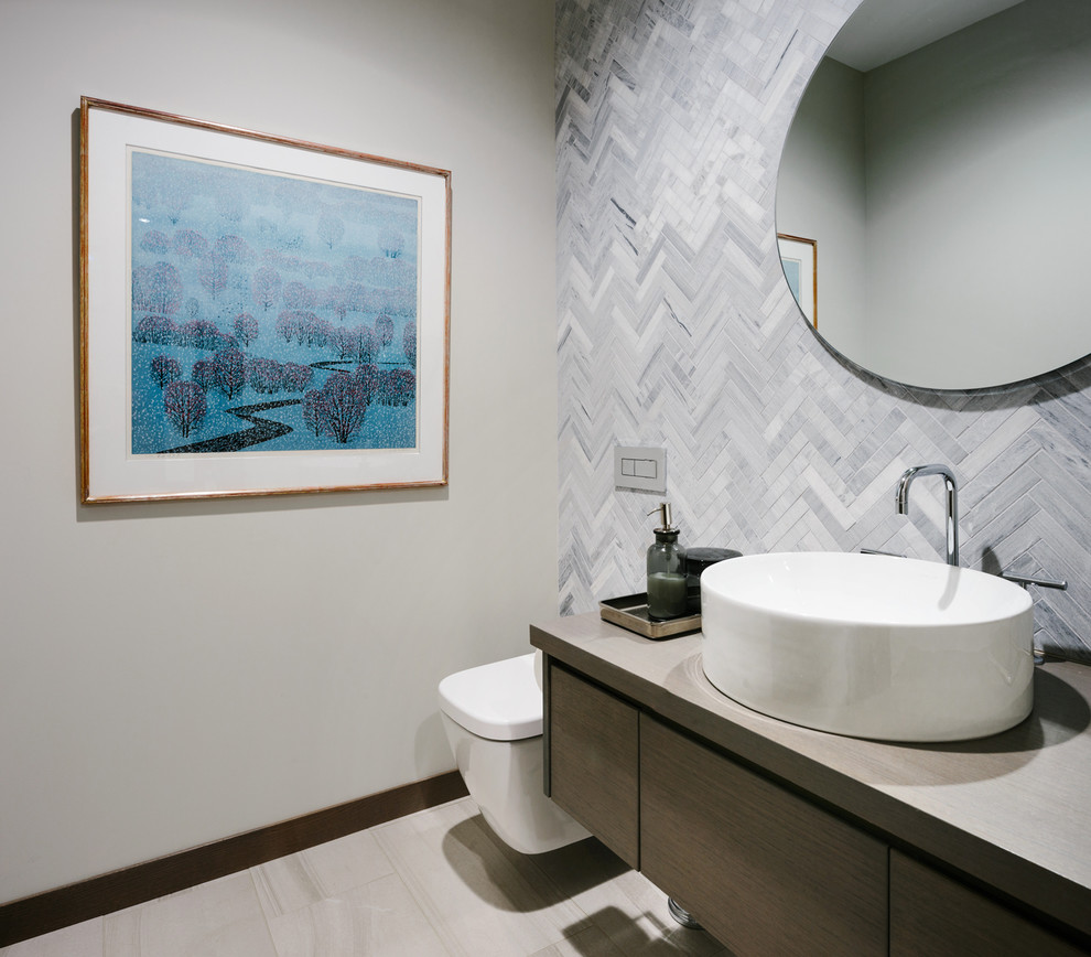 Inspiration for a large contemporary powder room in Vancouver with flat-panel cabinets, dark wood cabinets, a wall-mount toilet, gray tile, porcelain tile, beige walls, medium hardwood floors, a vessel sink, wood benchtops and grey floor.