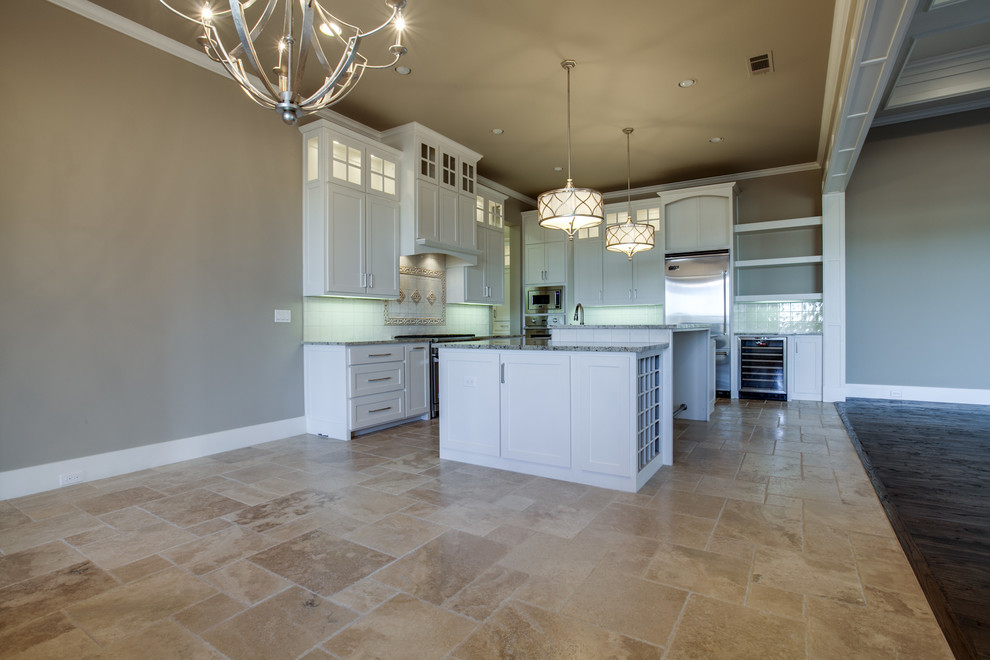 Example of a mid-sized transitional u-shaped limestone floor eat-in kitchen design in Dallas with a drop-in sink, shaker cabinets, white cabinets, granite countertops, white backsplash, subway tile backsplash, stainless steel appliances and an island