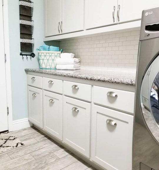 Design ideas for a mid-sized country dedicated laundry room in Las Vegas with shaker cabinets, grey cabinets, granite benchtops, white splashback, ceramic splashback, grey walls, ceramic floors, a side-by-side washer and dryer, grey floor and beige benchtop.