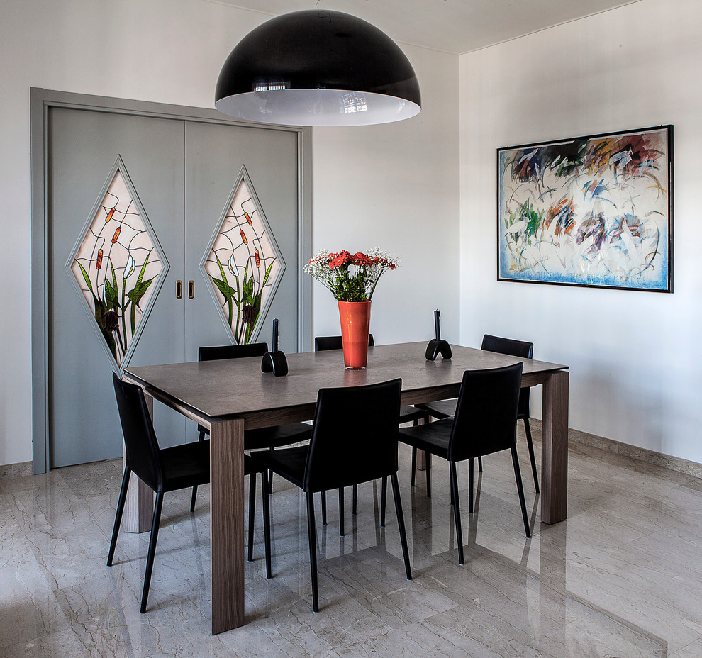 This is an example of a contemporary dining room in Milan with white walls and marble floors.