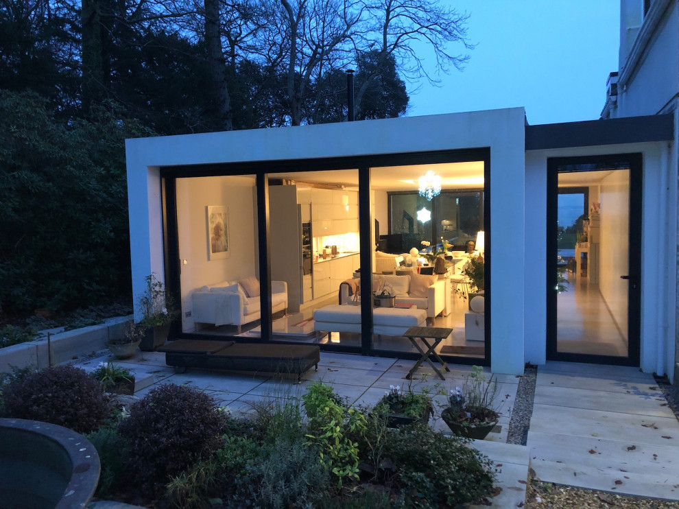 Large contemporary one-storey stucco white house exterior in Hampshire with a flat roof and a grey roof.