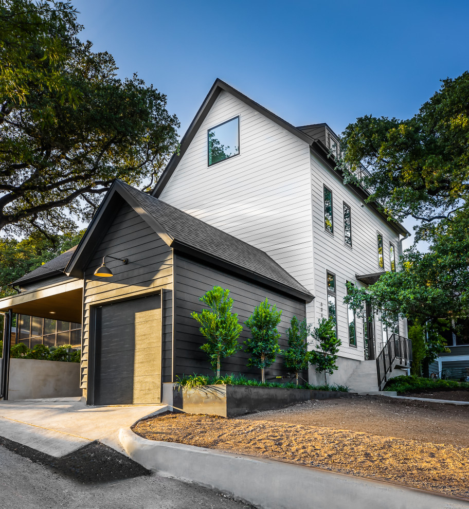 Mittelgroßes, Dreistöckiges Modernes Einfamilienhaus mit unterschiedlichen Fassadenmaterialien, weißer Fassadenfarbe, Satteldach, Schindeldach, schwarzem Dach und Verschalung in Austin