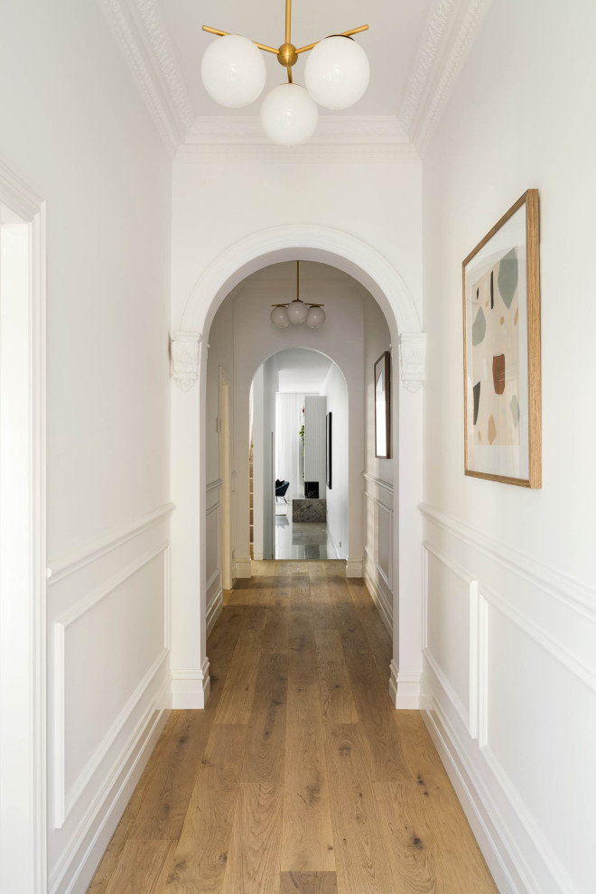 Mid-sized contemporary hallway in Melbourne with white walls, light hardwood floors and decorative wall panelling.