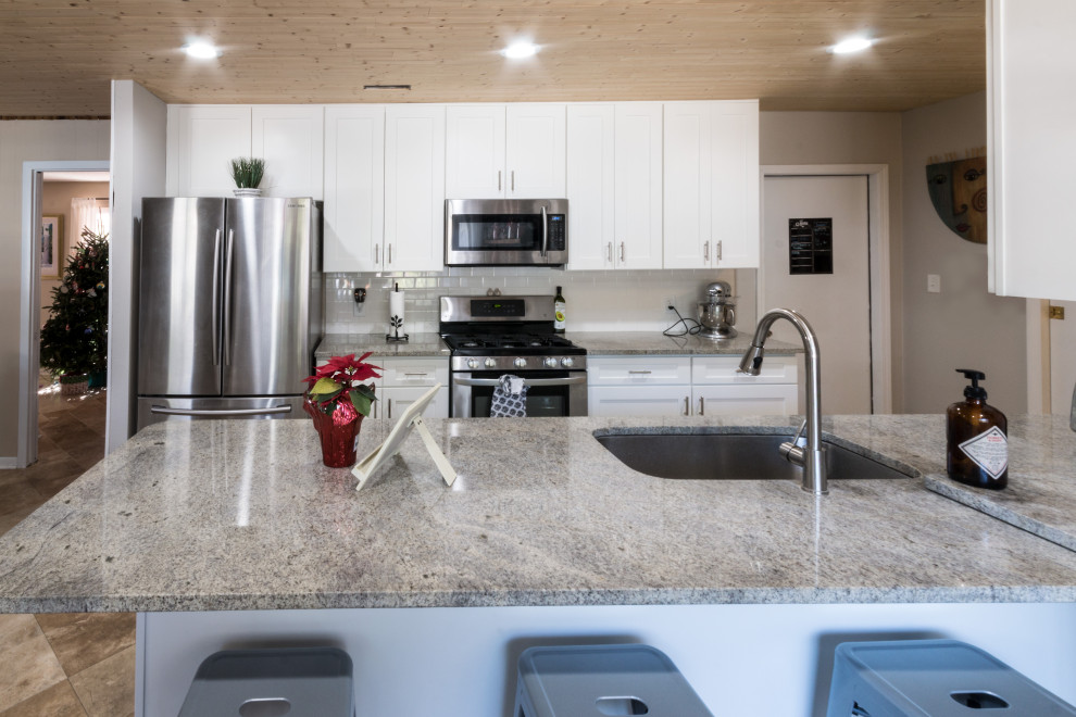 Inspiration for a small transitional cement tile floor and brown floor eat-in kitchen remodel with an undermount sink, shaker cabinets, white cabinets, granite countertops, white backsplash, cement tile backsplash, stainless steel appliances, a peninsula and white countertops