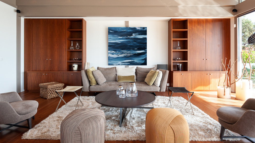 Ispirazione per un soggiorno design aperto con pareti bianche, pavimento in legno massello medio e pavimento marrone