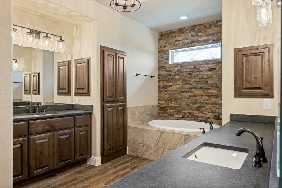 Inredning av ett rustikt badrum, med skåp i mörkt trä, ett platsbyggt badkar, en öppen dusch, mosaik, beige väggar, klinkergolv i småsten, ett undermonterad handfat och med dusch som är öppen