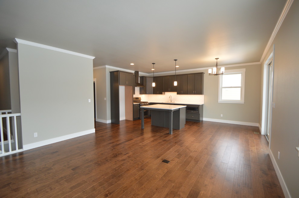 Mid-sized transitional l-shaped dark wood floor open concept kitchen photo with an undermount sink, shaker cabinets, brown cabinets, white backsplash, subway tile backsplash, an island and quartzite countertops