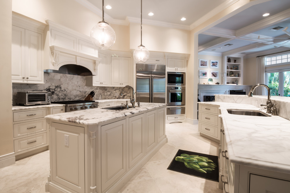 Large transitional u-shaped limestone floor and white floor open concept kitchen photo in Orlando with an undermount sink, raised-panel cabinets, white cabinets, marble countertops, gray backsplash, marble backsplash, stainless steel appliances and two islands