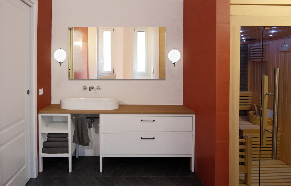 Inredning av ett nordiskt stort brun brunt badrum, med möbel-liknande, vita skåp, ett fristående badkar, en kantlös dusch, röd kakel, porslinskakel, vita väggar, klinkergolv i porslin, ett fristående handfat, träbänkskiva och grått golv