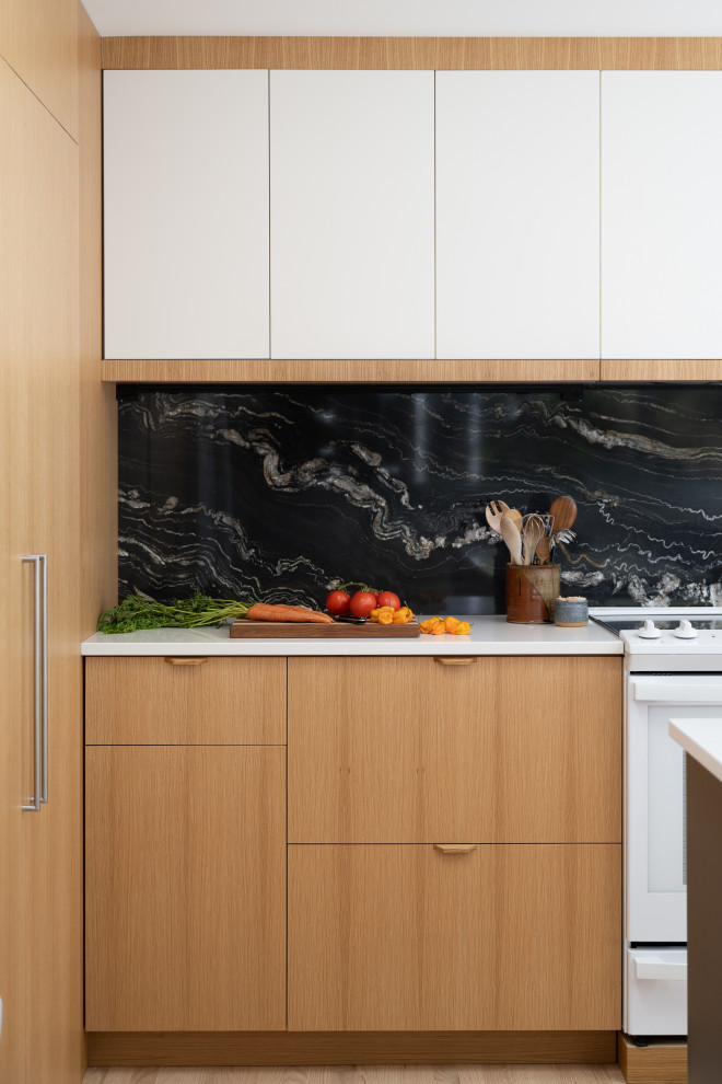 Mid-sized transitional l-shaped light wood floor kitchen photo in Indianapolis with an undermount sink, flat-panel cabinets, brown cabinets, quartz countertops, black backsplash, stone slab backsplash, white appliances, an island and white countertops