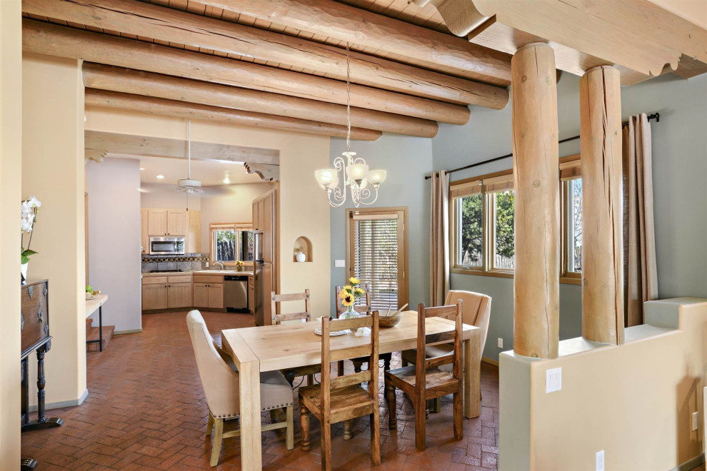 Idee per una sala da pranzo aperta verso la cucina stile americano di medie dimensioni con pavimento in mattoni, nessun camino, travi a vista, pareti grigie e pavimento rosso