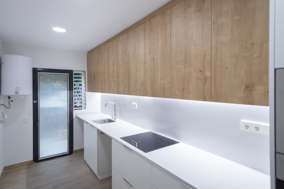 Example of a mid-sized trendy single-wall ceramic tile and brown floor enclosed kitchen design in Barcelona with a single-bowl sink, flat-panel cabinets, white cabinets, white backsplash, stainless steel appliances, no island and white countertops