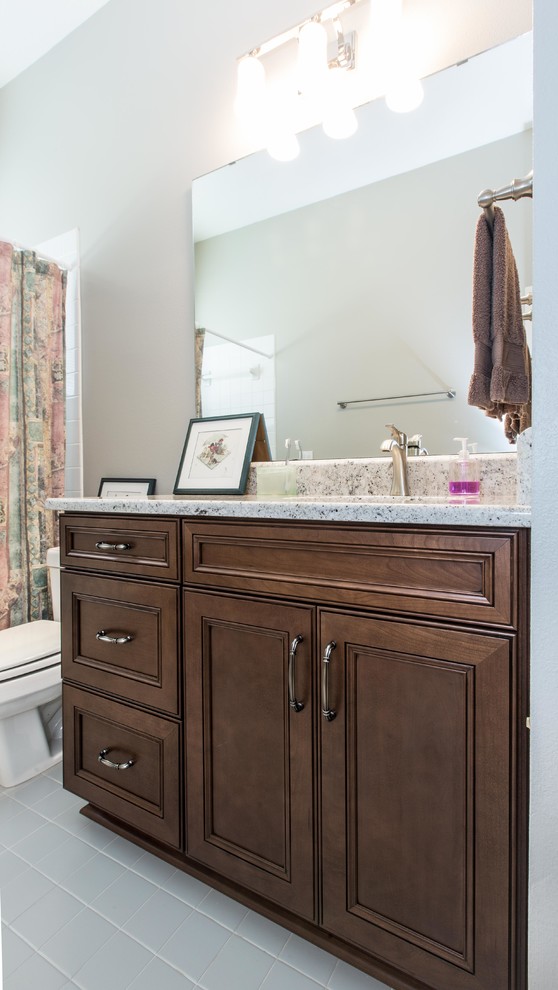 Design ideas for a mid-sized traditional bathroom in Orlando with flat-panel cabinets, brown cabinets, an undermount sink and granite benchtops.