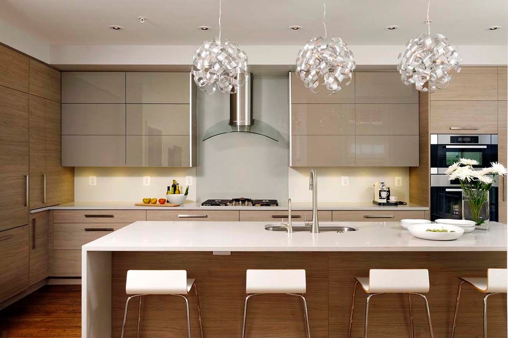 Design ideas for a mid-sized contemporary galley eat-in kitchen in Toronto with a single-bowl sink, flat-panel cabinets, beige cabinets, quartzite benchtops, grey splashback, glass sheet splashback, stainless steel appliances, light hardwood floors, with island, brown floor and white benchtop.