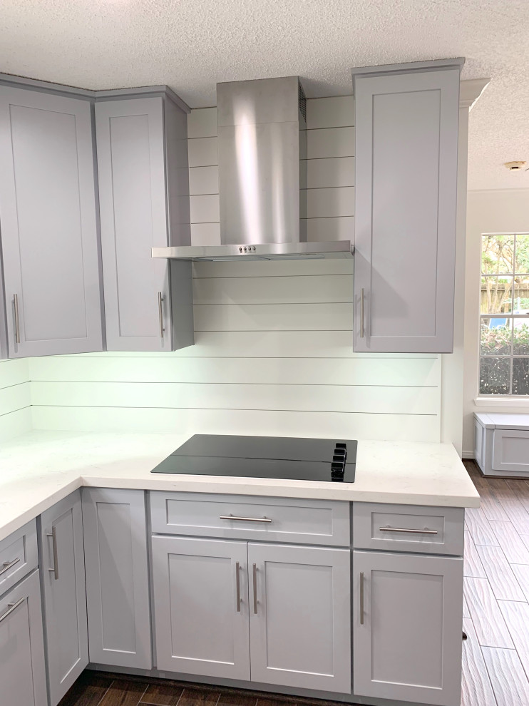 This is an example of a mid-sized transitional kitchen in Houston with a single-bowl sink, shaker cabinets, grey cabinets, quartzite benchtops, white splashback, shiplap splashback, stainless steel appliances, laminate floors, brown floor and white benchtop.