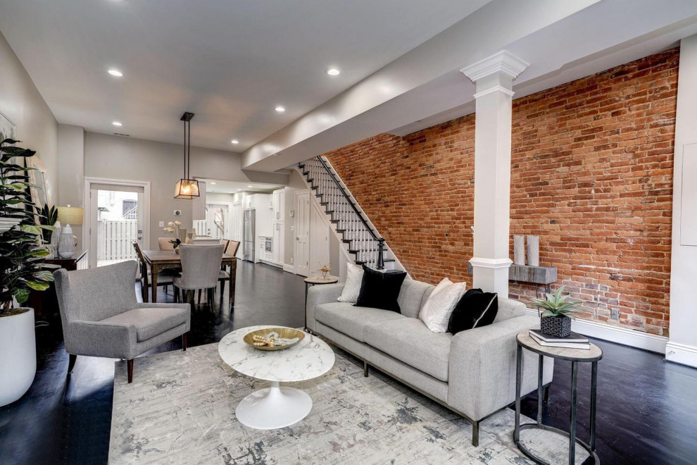 Photo of a medium sized classic walk-out basement in DC Metro with grey walls, dark hardwood flooring, a standard fireplace, a brick fireplace surround, black floors and feature lighting.