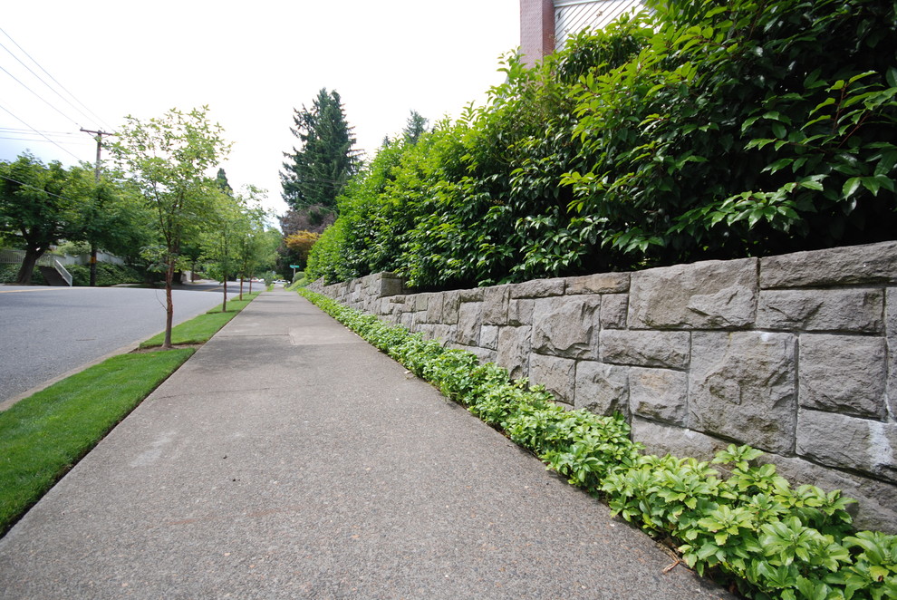 This is an example of a mid-sized traditional side yard garden in Portland with a retaining wall.