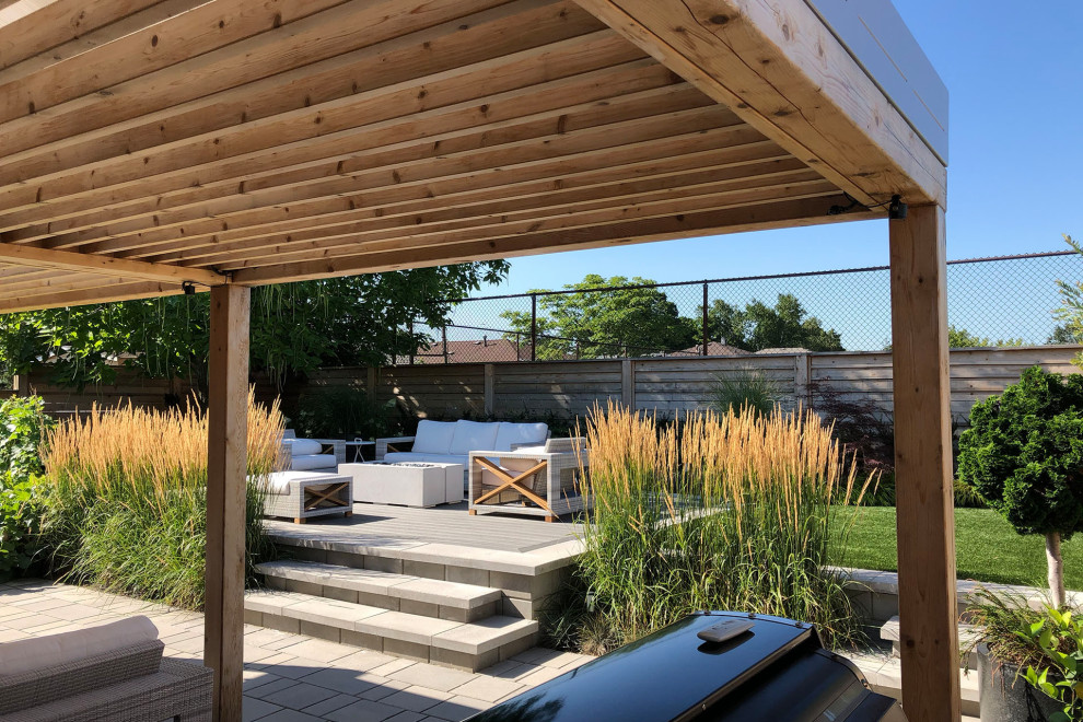 Beach style backyard patio in Toronto with concrete pavers and a pergola.