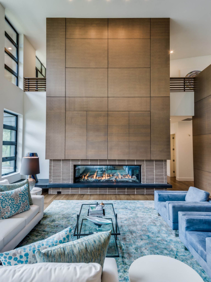 Contemporary open concept living room in Dallas with white walls, medium hardwood floors, a ribbon fireplace, a tile fireplace surround, a concealed tv and brown floor.