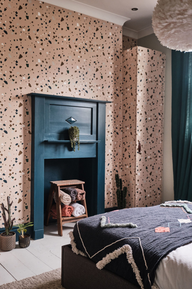 Inspiration for a mid-sized eclectic guest bedroom in London with blue walls, painted wood floors, a standard fireplace, a wood fireplace surround, white floor, vaulted and wallpaper.