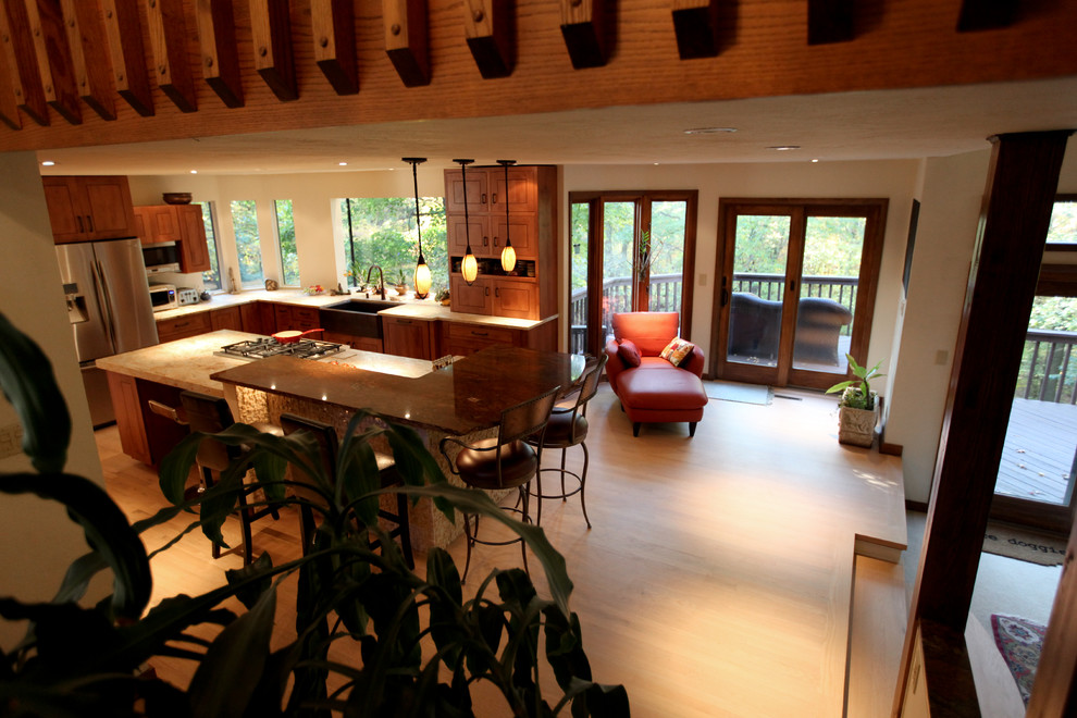 Large transitional u-shaped light wood floor enclosed kitchen photo with a farmhouse sink, shaker cabinets, dark wood cabinets, granite countertops, beige backsplash, stainless steel appliances and an island