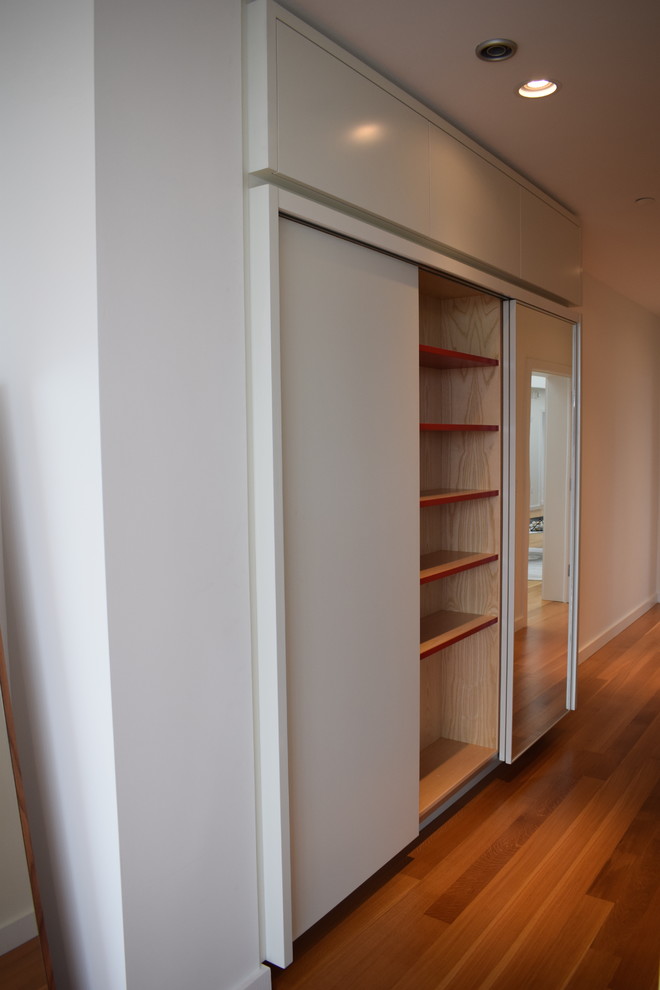 This is an example of a mid-sized transitional gender-neutral built-in wardrobe in Boston with open cabinets, medium hardwood floors and brown floor.
