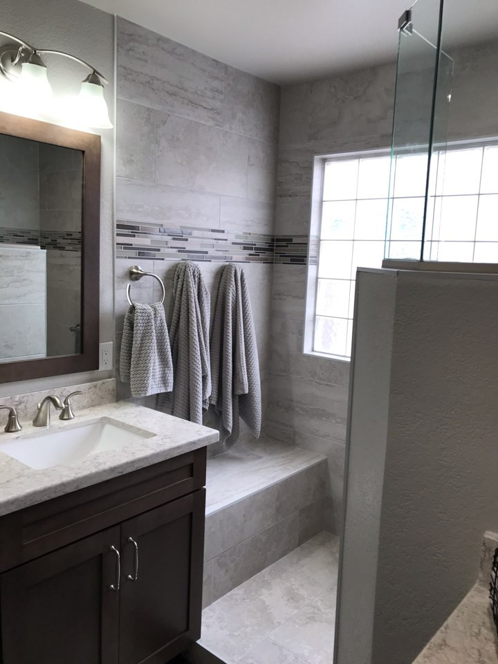 This is an example of a large beach style master bathroom in Phoenix with shaker cabinets, dark wood cabinets, an open shower, gray tile, porcelain tile, grey walls, vinyl floors, an integrated sink, quartzite benchtops, grey floor, an open shower, grey benchtops, a niche, a double vanity and a built-in vanity.