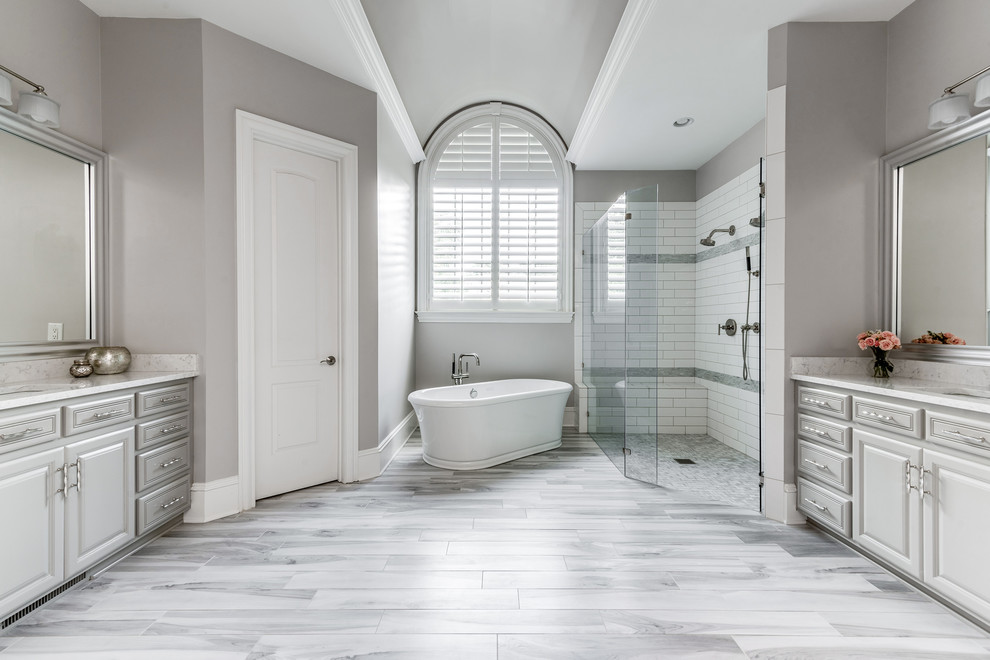 Large transitional master bathroom in Charlotte with grey cabinets, a freestanding tub, a curbless shower, gray tile, terra-cotta tile, grey walls, porcelain floors, an undermount sink, engineered quartz benchtops, grey floor, a hinged shower door and grey benchtops.