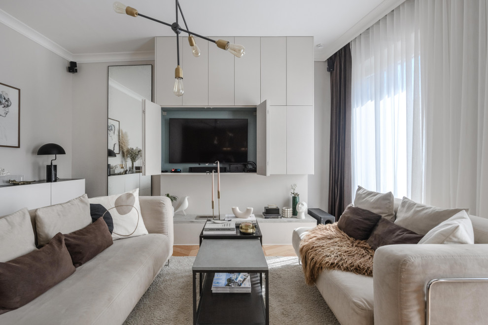 Esempio di un piccolo soggiorno contemporaneo con pareti beige, parquet chiaro e TV nascosta