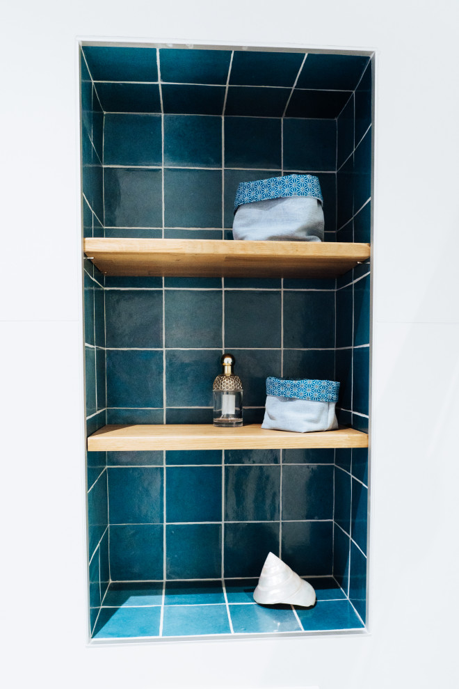 Cette image montre une salle de bain principale nordique de taille moyenne avec des portes de placard bleues, une douche à l'italienne, un bidet, un carrelage blanc, des carreaux de céramique, un mur bleu, un sol en carrelage de céramique, un lavabo de ferme, un plan de toilette en marbre, un sol blanc, une cabine de douche à porte coulissante, un plan de toilette blanc, une niche et meuble simple vasque.