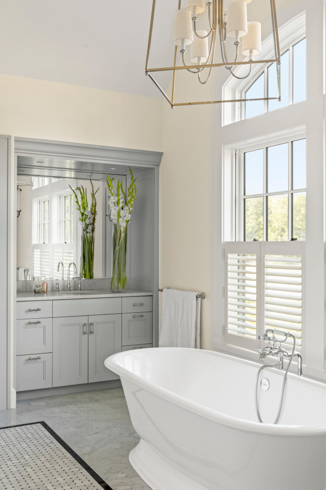 This is an example of a country bathroom in Boston with grey cabinets, a freestanding tub, an alcove shower, a one-piece toilet, beige walls, mosaic tile floors, quartzite benchtops, grey floor, a hinged shower door and grey benchtops.