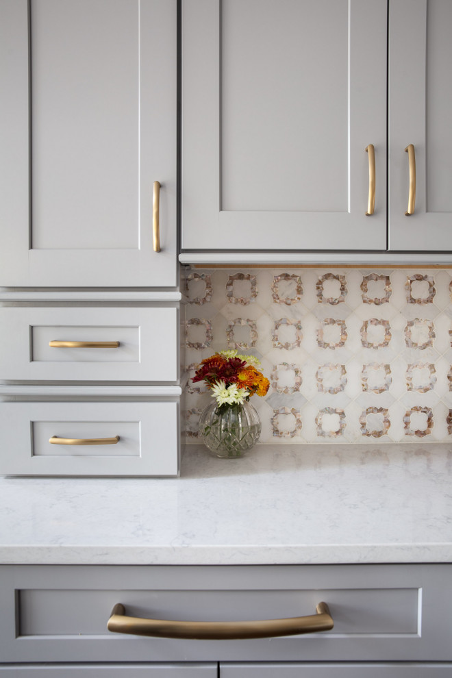 Inspiration for a transitional dark wood floor and brown floor kitchen remodel with a drop-in sink, shaker cabinets, gray cabinets, quartzite countertops, white backsplash, mosaic tile backsplash, stainless steel appliances, an island and white countertops