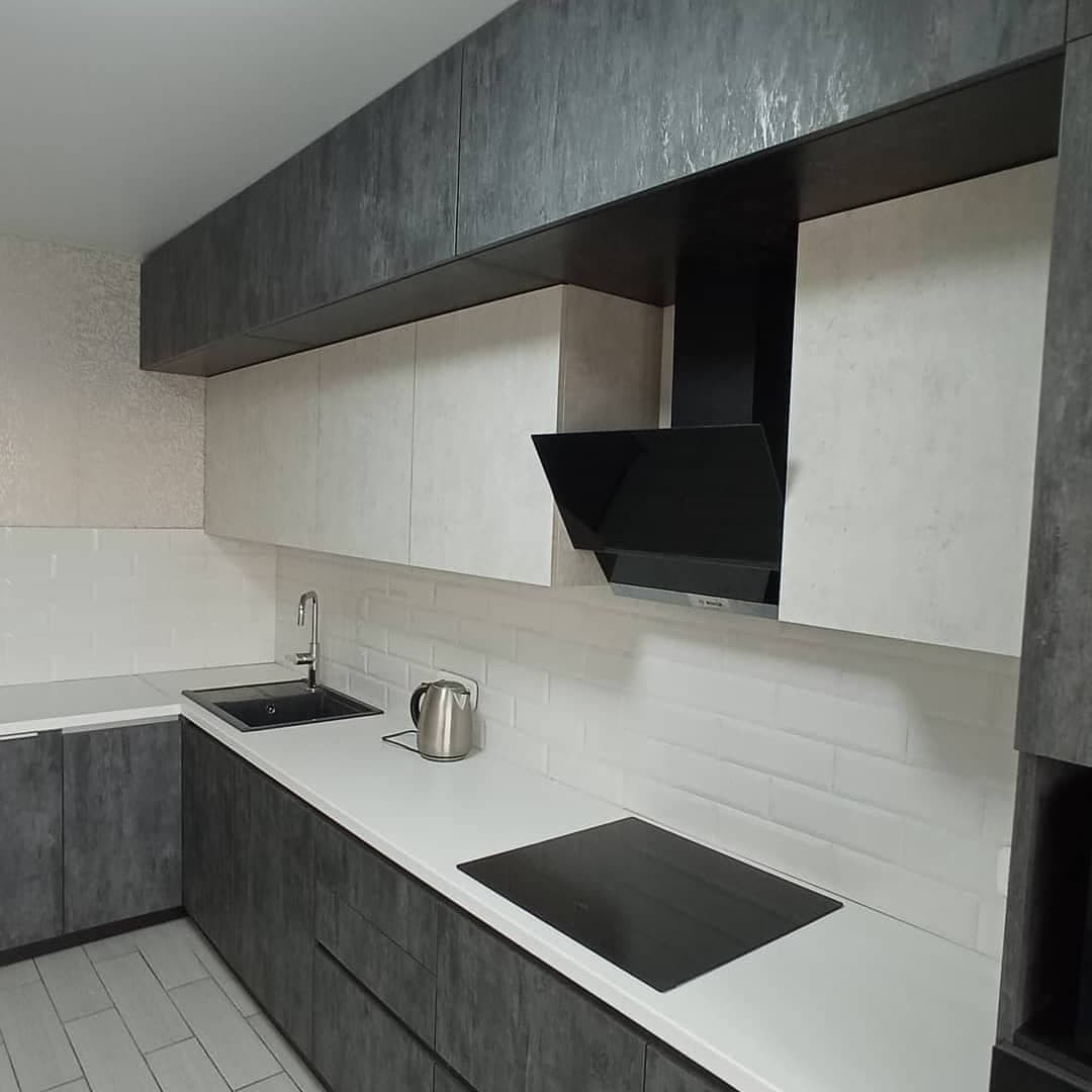 Широкая угловая черно-белая кухня с фасадами под камень