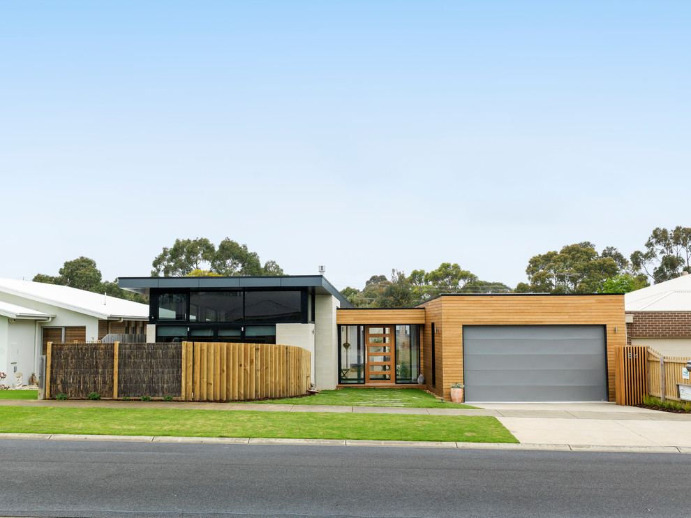 This is an example of a contemporary one-storey house exterior in Melbourne with mixed siding and a flat roof.